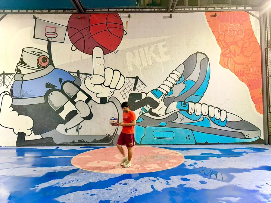 Playing football on a blue court in front of a large graffiti mural