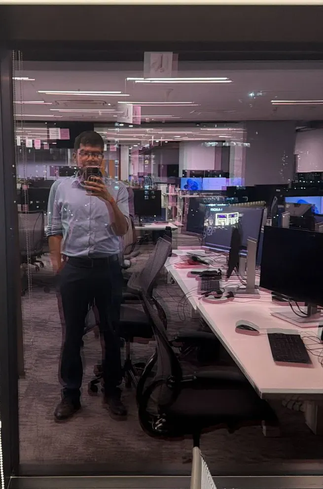 Reflection in an office window showing an empty floor of desks at night